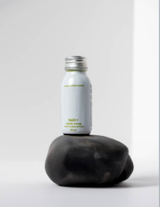 NEU+ NAD+ Shot 60ml bottle on a stone